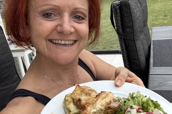Manuela hält lachend einen bunten Teller mit Salat und Fleisch