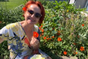 Manuela im Sommergarten mit orangen Blüten, Sommer mit mehr Energie und weniger Kilos