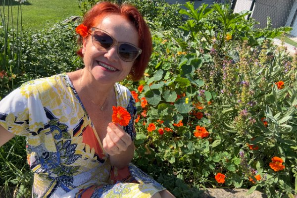 Manuela im Sommergarten mit orangen Blüten, Sommer mit mehr Energie und weniger Kilos